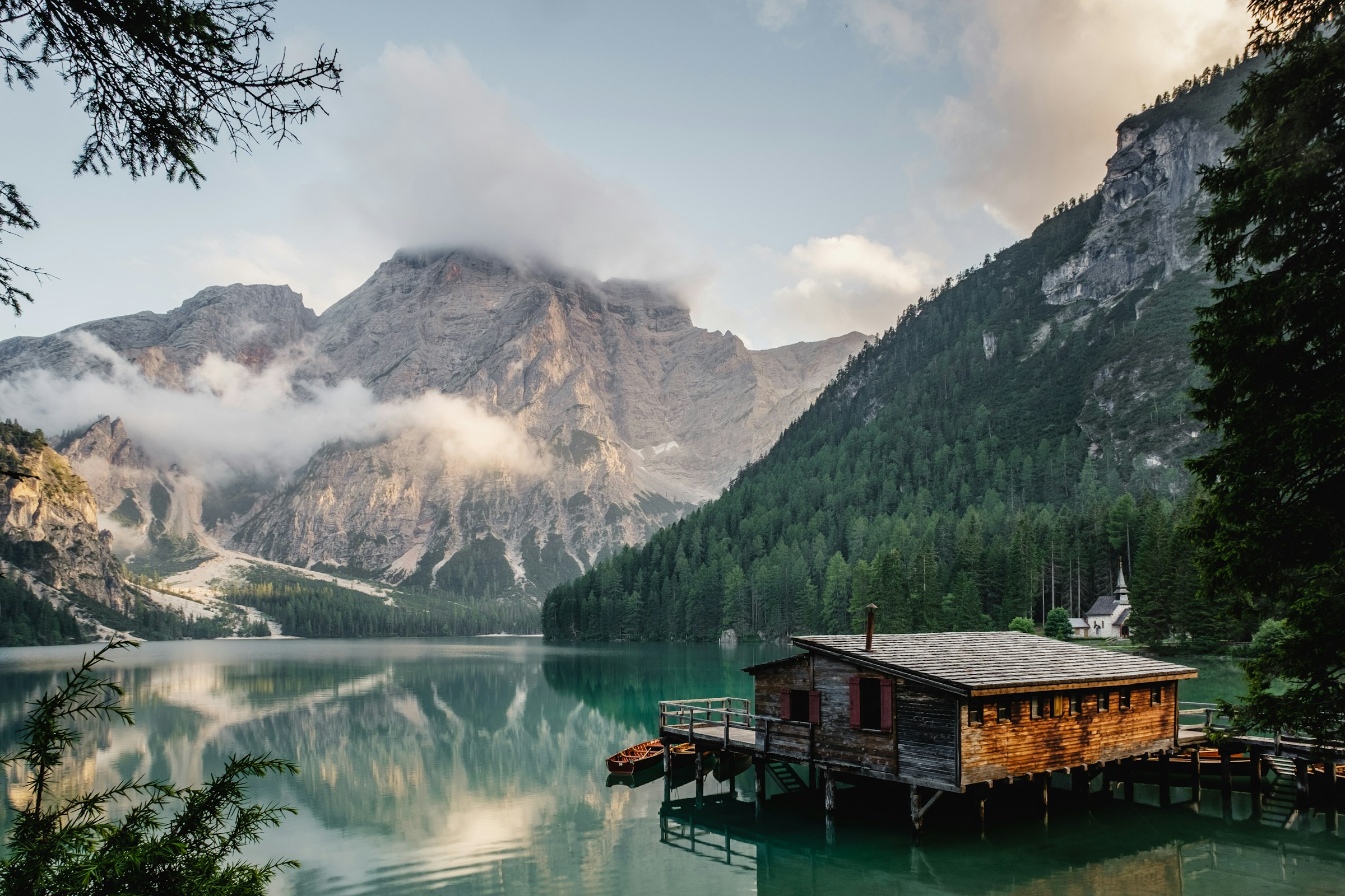 Alpine lake at dawn with timber boathouse and mountain reflection