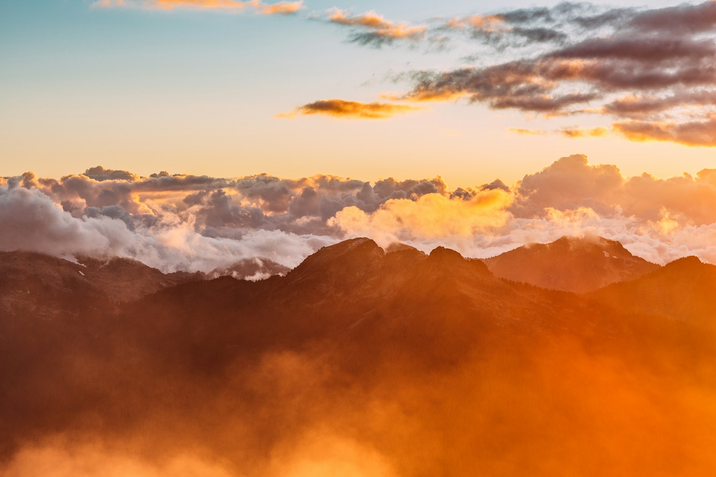 Golden sunset clouds rolling across mountain peaks at altitude