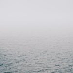 Calm grey sea fading into soft fog at the horizon